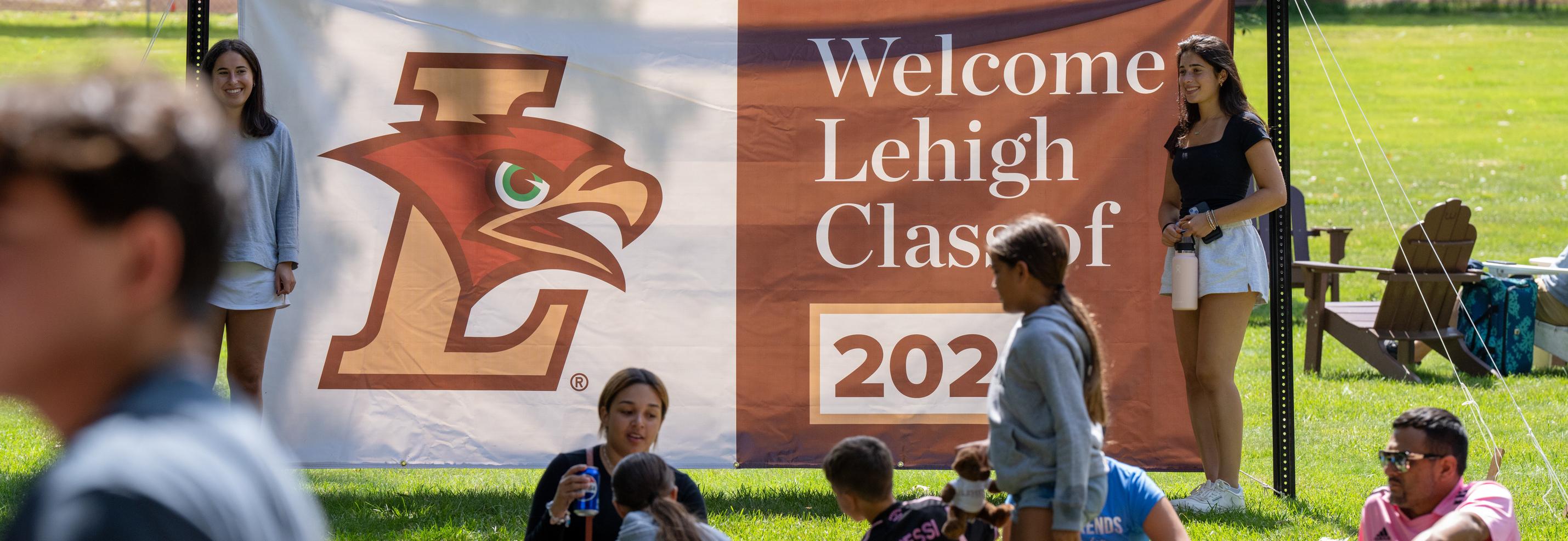 Students in front of welcome sign on campus lawn